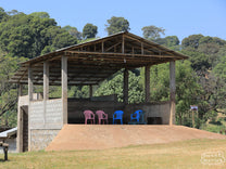 Blue and red chairs under a shade canopy of a wet mill near Bobea.