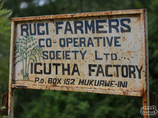 The weathered, but beautifully hand-painted sign at Igutha factory that states it's part of Rugi Farmers Cooperative Society, and has an illustration of a coffee shrub.