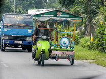 A tuk tuk driver and his green scooter putting down the streets of Central Aceh.