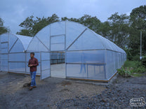 Aulia outside covered solar coffee drying rooms at a processing site in Aceh.