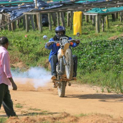 This coffee farmer shows off his wheelie skills on a dirt bike in front of the raised drying beds at the Mutovu coffee washing station in Nyamasheke, Rwanda.