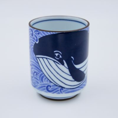 The Sad Whale Ceramic Cup is adorned with indigo blue whales swimming through water.