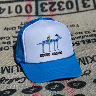 The Blue Chucho Summer Camp Hat features a spotted blue chucho serving up a hot cup of coffee.