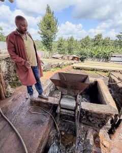 Farm manager Moses surveys the small pulper used at Spike, and coffee dries on raised beds in the background. Kiambu, Kenya.